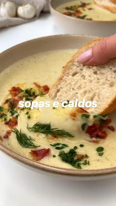 a hand is dipping bread into a bowl of soup