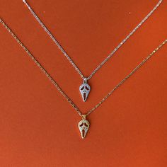 three necklaces with charms on an orange background