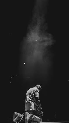 black and white photograph of a man kneeling on the ground in front of a spotlight