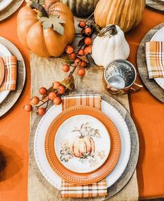 the table is set with pumpkins, gourds and dishes