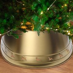 a small christmas tree in a gold bowl on a wooden table with lights around it