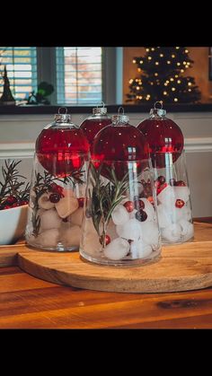 three glass vases filled with red and white decorations on top of a wooden table