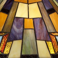 a stained glass lamp hanging from the side of a ceiling fixture with multiple colors on it