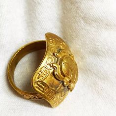 a gold ring with an image of a lion on the front and side, sitting on top of a white cloth