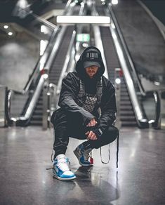 a man sitting on the ground in front of an escalator with his foot up