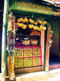 a fruit stand with bananas, apples and oranges on display in front of it