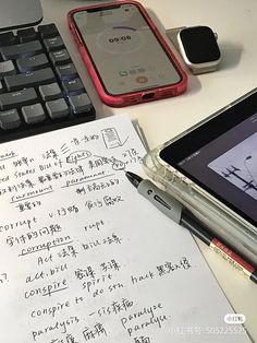 a cell phone sitting on top of a desk next to a keyboard and mouse with writing on it