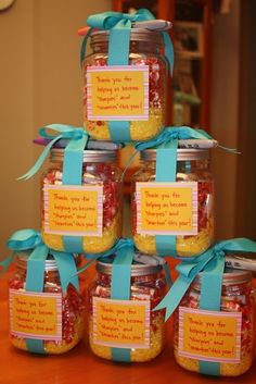 there are many jars that have candy in them on the table with blue ribbons and tags