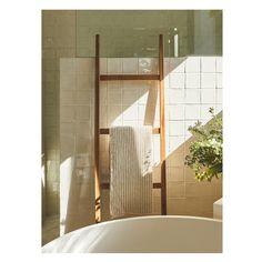 a towel rack in the corner of a bathroom with a bathtub and toilet nearby