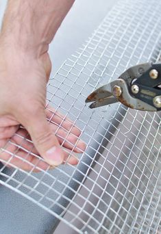 a person is cutting metal mesh with scissors