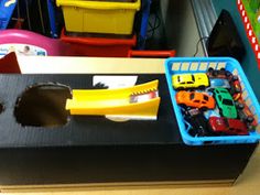 toy cars are sitting on top of a black box in a playroom with other toys