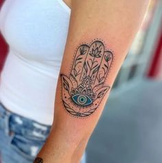 a woman's arm with a hamsa tattoo on it and an eye in the middle