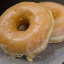 two glazed donuts sitting on top of a piece of wax paper