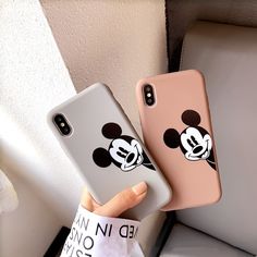 two iphone cases with mickey mouse faces on them, one is pink and the other is white