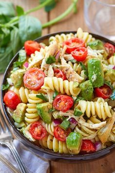 a bowl filled with pasta salad on top of a wooden table