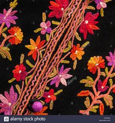 colorful embroidered fabric with flowers and beads on black background - stock image, close up