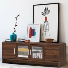 a wooden entertainment center with various items on it and a framed art piece in the background