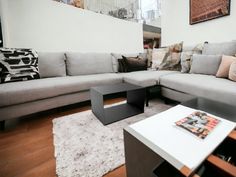 a living room filled with lots of furniture and pillows on top of a wooden floor