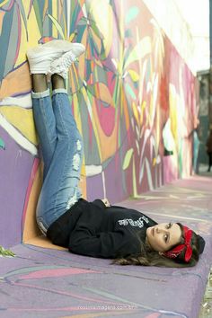 a woman laying on the ground next to a colorful wall