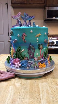 a blue cake with sea creatures on it sitting on a table in front of an oven