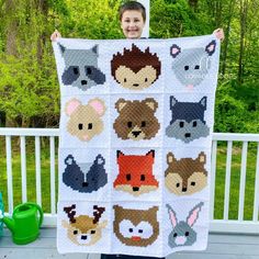 a person holding up a quilt with animals on it