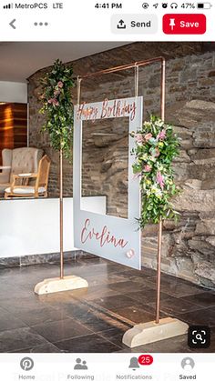 a sign that says happy birthday next to some flowers and greenery on the side of a stone wall