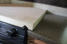 a stove top sitting on top of a counter next to a wooden shelf with knobs