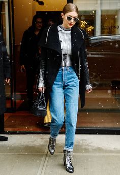 a woman in black jacket and jeans walking down the street