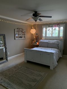 a bed room with a neatly made bed next to a mirror and a ceiling fan