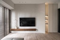 a living room with white walls and wooden flooring has a flat screen tv on the wall