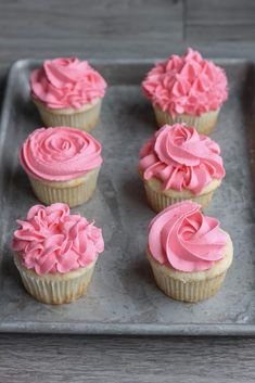 cupcakes with pink frosting on a baking sheet