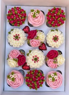 cupcakes decorated with pink and white frosting in a box