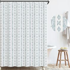 a white and blue shower curtain hanging on a wall next to a bathtub in a bathroom