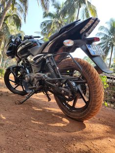 a black motorcycle parked on top of a dirt road