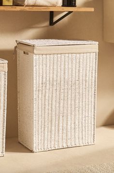 two white wicker baskets sitting next to each other on top of a shelf in a bathroom