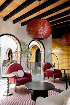 a living room filled with lots of furniture and hanging lanterns over the top of it