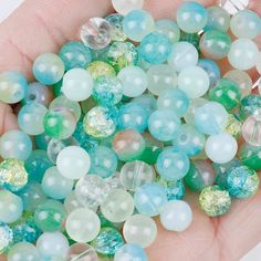 a hand is holding some glass beads in it's palm, while another person holds them up to the camera