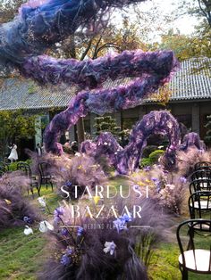 chairs and tables are set up outside in the grass, with purple flowers on them