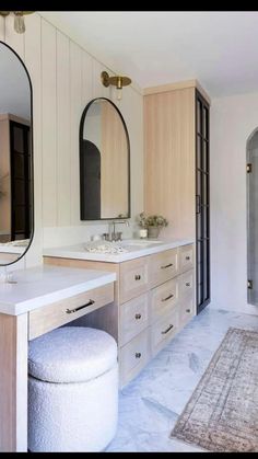 a large bathroom with two sinks, mirrors and an ottoman in the middle of it