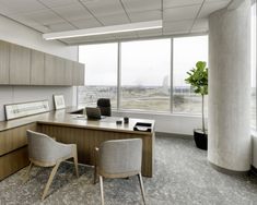 an empty office with two chairs and a desk in front of large windows overlooking the city