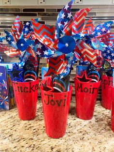 red, white and blue plastic cups with streamers in them sitting on a counter