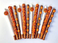 several sticks decorated with basketballs and orange sprinkles are arranged in a row on a white surface