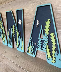 the letters are made out of wood and have seaweed on them, along with other marine animals