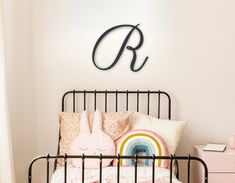 a child's bed with a black metal headboard and pink pillows