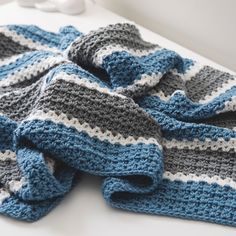 there is a crocheted blue and gray blanket on the table