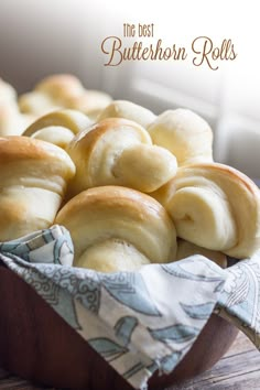 a wooden bowl filled with rolls on top of a table