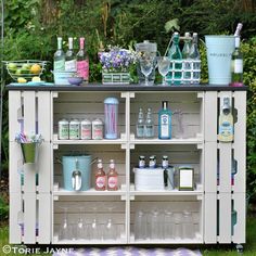 an outdoor bar with lots of bottles and glasses on the top shelf in front of it