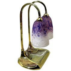 a purple and white lamp sitting on top of a metal stand next to a glass vase