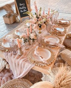 the table is set with pink flowers and plates