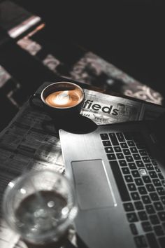 an open laptop computer sitting on top of a table next to a cup of coffee